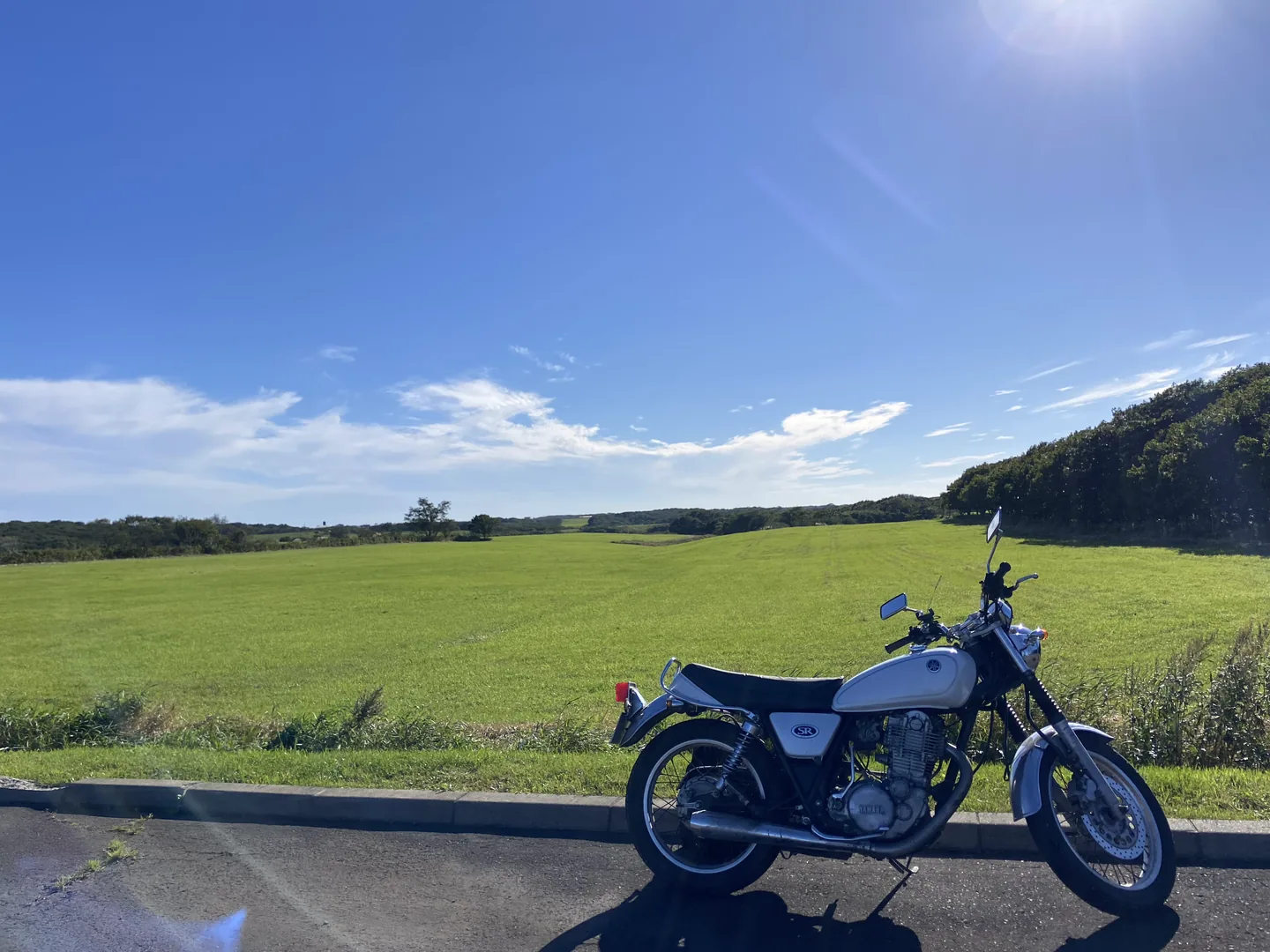 牧草地の脇に停めたSR400と青空